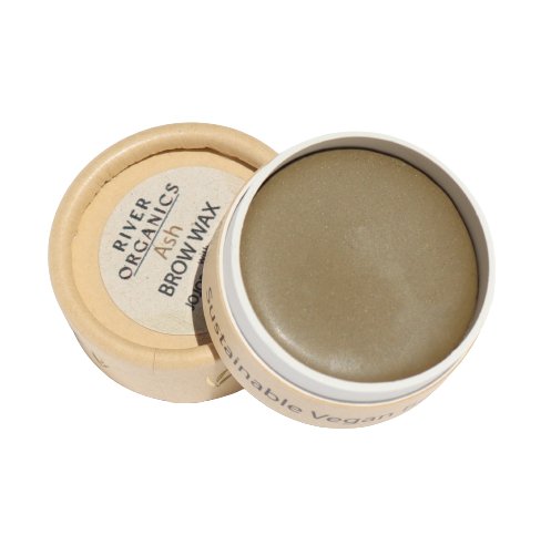 A small, round container with a removable lid is shown. The container's label reads "River Organics Tinted Vegan Eyebrow Wax | Ash" and "Vegan Certified." The eco-friendly packaging showcases a solid, ash-colored, tinted brow wax in neutral tones.