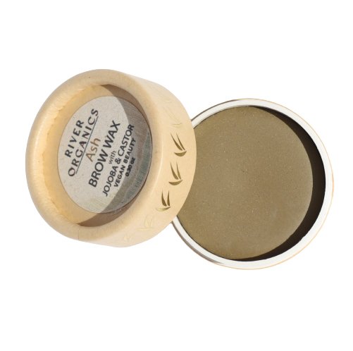 A small bamboo container with the lid partially off reveals tinted brow wax inside. The lid has "River Organics Tinted Vegan Eyebrow Wax | Ash" written on it along with "Jojoba + Castor, Vegan Certified." The smooth, beige wax is encased in a round, eco-friendly container, perfect for conscious beauty routines.