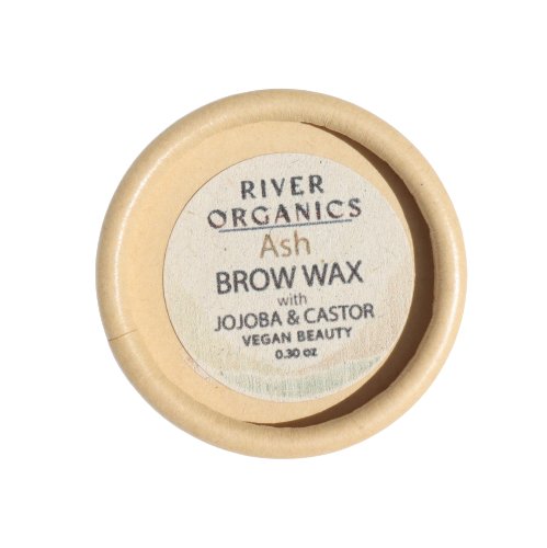 A round container of River Organics Tinted Vegan Eyebrow Wax | Ash sits elegantly. The label on the lid reads, "River Organics Tinted Vegan Eyebrow Wax | Ash with Jojoba & Castor Vegan Beauty 0.30 oz." This eco-friendly, vegan-certified product features a beige container with a matching lid.