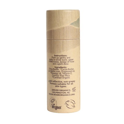 The Illumi Vegan Highlighter Stick - Golden Hue by River Organics comes in a cylindrical cardboard tube with a cap, showcasing instructions and ingredients. This sustainable packaging emphasizes "vegan" and contains shea butter, cocoa butter, and avocado oil for a dewy look.